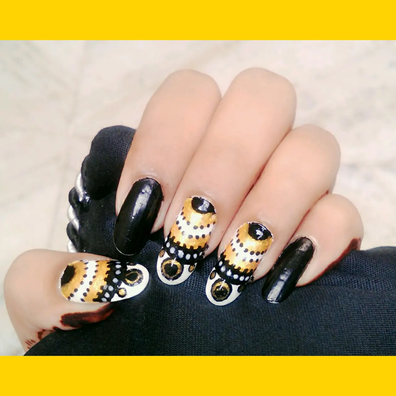 Glossy black nails with gold and white graphic accent nail art