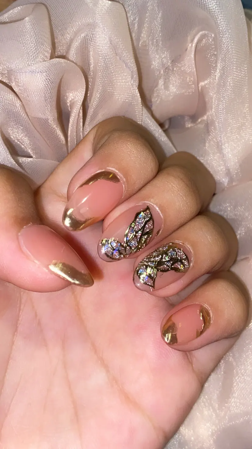 Nude almond nails with gold edging, butterfly art, and crystal details