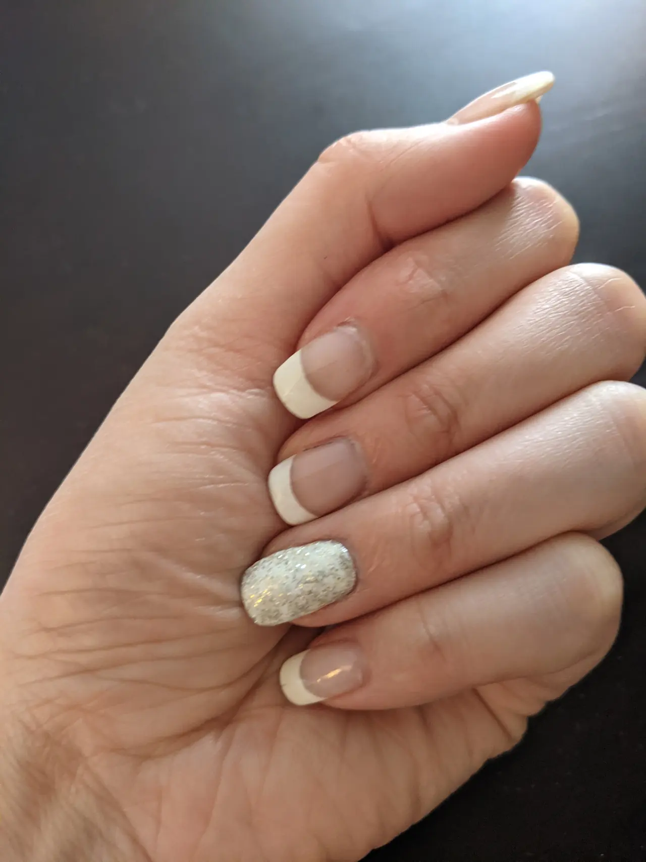 Sheer nude nails with white French tips and a silver glitter accent nail